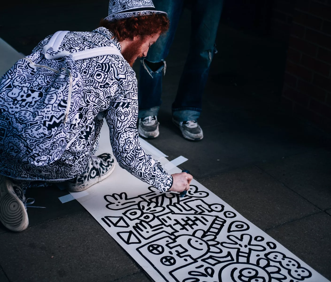 male artist Mr. Doodle drawing on white paper while kneeling at daytime